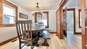 A dining area with a wooden table and chairs, a chandelier, and a view of a hallway. - The Vintage Lake House w/ Private Dock (Russells Point)