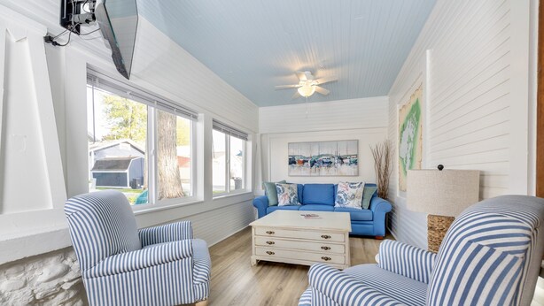 A room with striped armchairs, a blue sofa, a wooden coffee table, and a ceiling fan. - The Vintage Lake House w/ Private Dock (Russells Point)