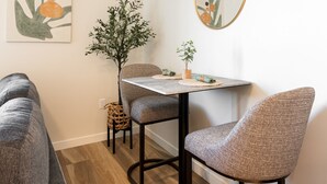 Un coin repas moderne avec une table ronde, deux chaises, une petite plante en pot et un miroir fixé au mur.
