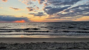 En strand med bølger og en solnedgang.