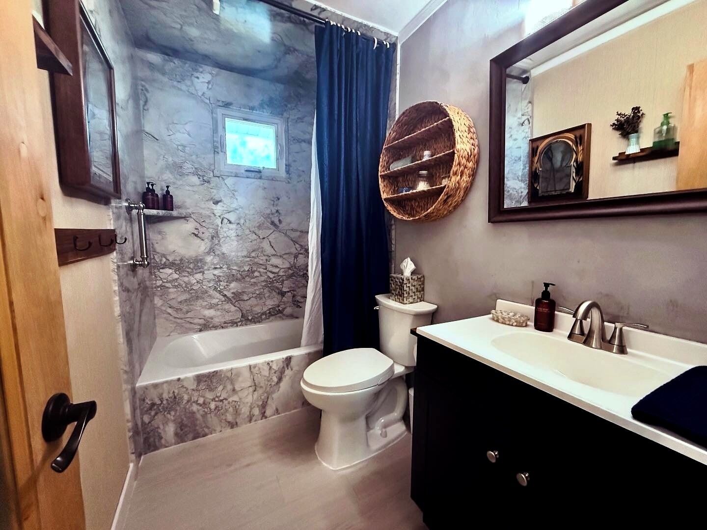 Ein Badezimmer mit Marmorwand, einer Badewanne, einer Toilette und einem Waschtisch mit Spiegel.