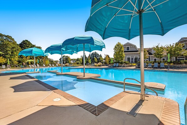 Relax by the pool surrounded by lounge chairs and umbrellas, with steps leading into the water.
