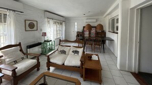 Un salón espacioso con un sofá de madera, una mesa de comedor con sillas y una pequeña mesita auxiliar.