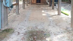 A wooden structure with a covered area, a visible electrical box, and a sandy ground.
