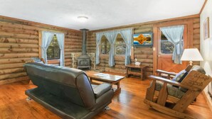 A log cabin interior with a sofa, a rocking chair, a table, and a fireplace. - Carters Lake Lakeside Log Cabin #2 includes boat slip at the marina (Ellijay)