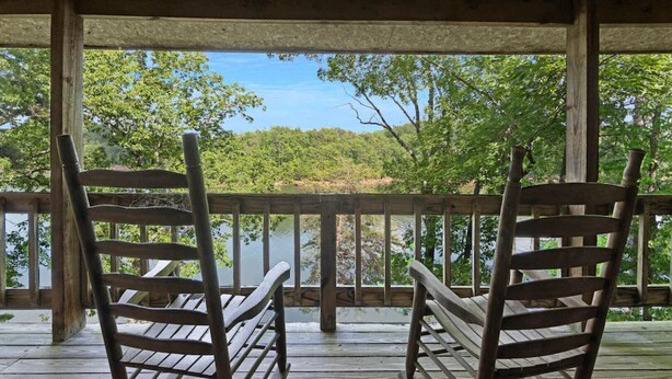 A wooden deck with two rocking chairs overlooking a lake and forest. - Carters Lake Lakeside Log Cabin #2 includes boat slip at the marina (Ellijay)