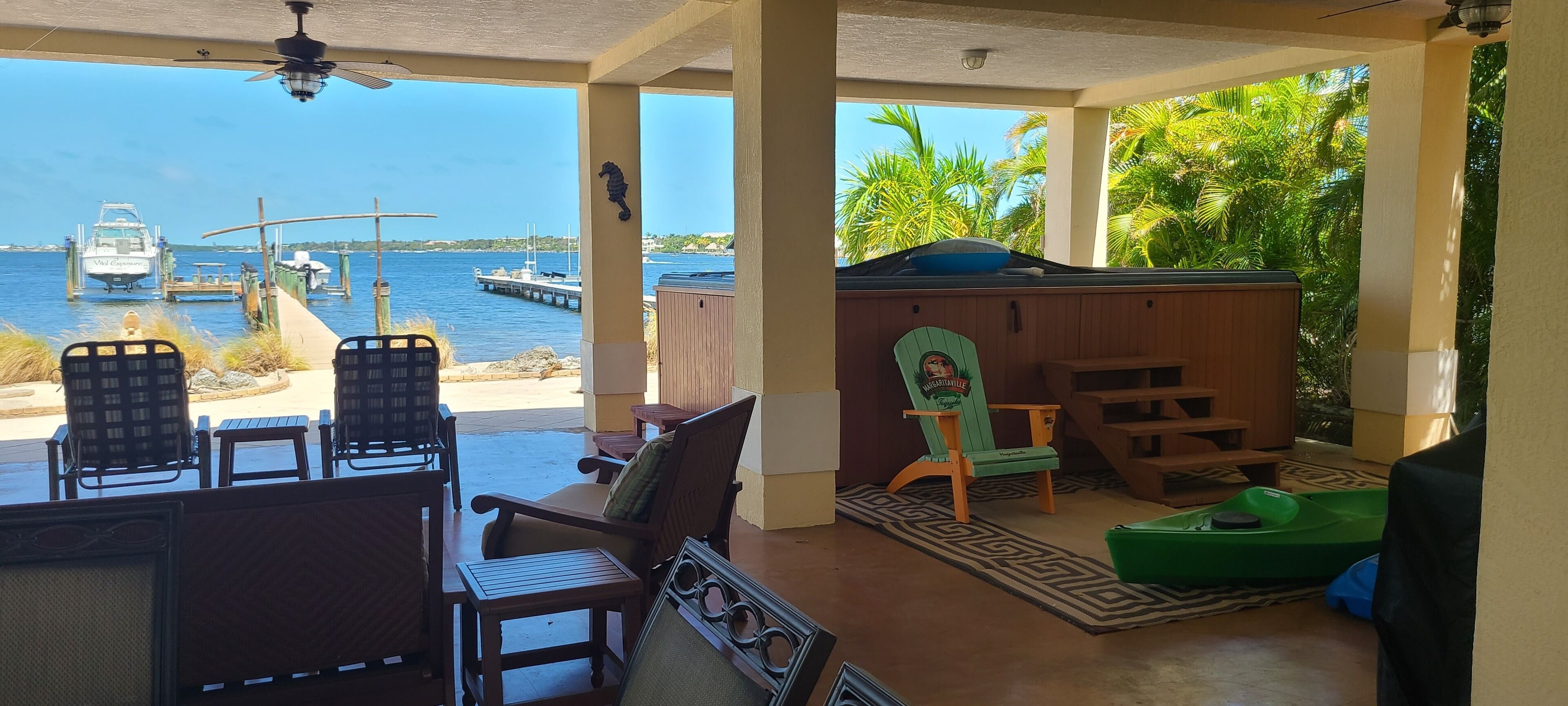 A covered outdoor seating area with a view of the water and docked boats.