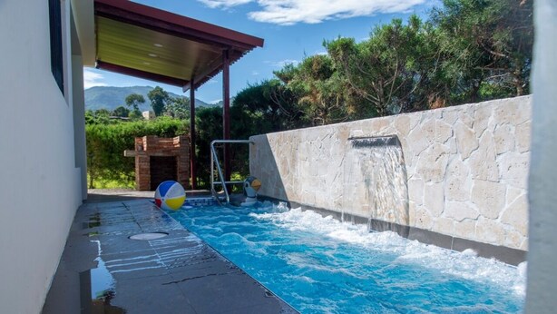 A swimming pool with a stone wall and a brick structure. - Villa Dorada Jarabacoa (Jarabacoa)