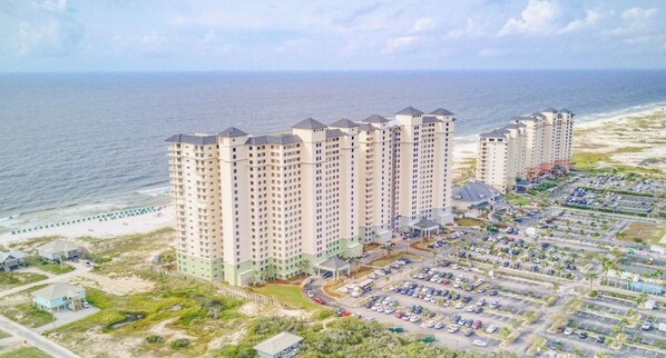 Un hôtel de grande hauteur, avec de nombreux étages, un parking et une vue sur la plage.