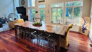 A spacious dining area with a large wooden table, chairs, and a stone accent wall. - 5-Bedroom Custom Lakefront Home on Lake Norman-Private Dock, PaddleBoards/Kayaks (Catawba)