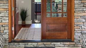 A wooden door with a glass panel, set in a stone wall. - 5-Bedroom Custom Lakefront Home on Lake Norman-Private Dock, PaddleBoards/Kayaks (Catawba)