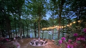 A circular outdoor seating area surrounded by trees, with string lights overhead. - 5-Bedroom Custom Lakefront Home on Lake Norman-Private Dock, PaddleBoards/Kayaks (Catawba)