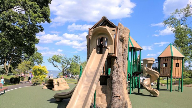 A playground with a slide, climbing structures, and a treehouse.