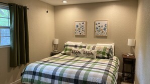 A bedroom with a checkered bedspread, two wall-mounted lamps, and two framed floral artworks. - ￼  Peaceful Two Bedroom Guest House near Wekiva River and State Parks ￼ (Sorrento)