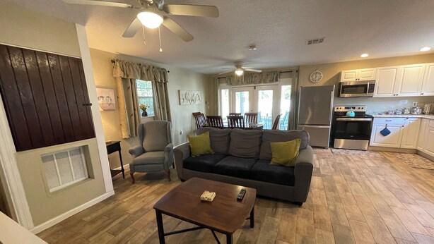 A living room with a sofa, armchairs, a coffee table, and a ceiling fan. There is a kitchen area with appliances and cabinets. - ￼  Peaceful Two Bedroom Guest House near Wekiva River and State Parks ￼ (Sorrento)