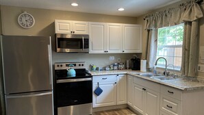 A kitchen with white cabinets, stainless steel appliances, a clock, and a window with curtains. - ￼  Peaceful Two Bedroom Guest House near Wekiva River and State Parks ￼ (Sorrento)