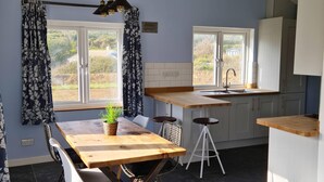 Une cuisine moderne avec une table et des chaises en bois, un évier et une fenêtre avec des rideaux.