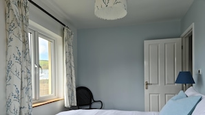 Une chambre à coucher avec un lit, une chaise, une lampe et une porte.