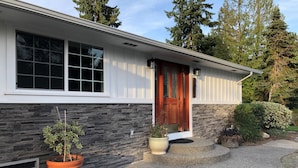 Una casa moderna con fachada de piedra, puerta principal de madera y un ventanal grande.