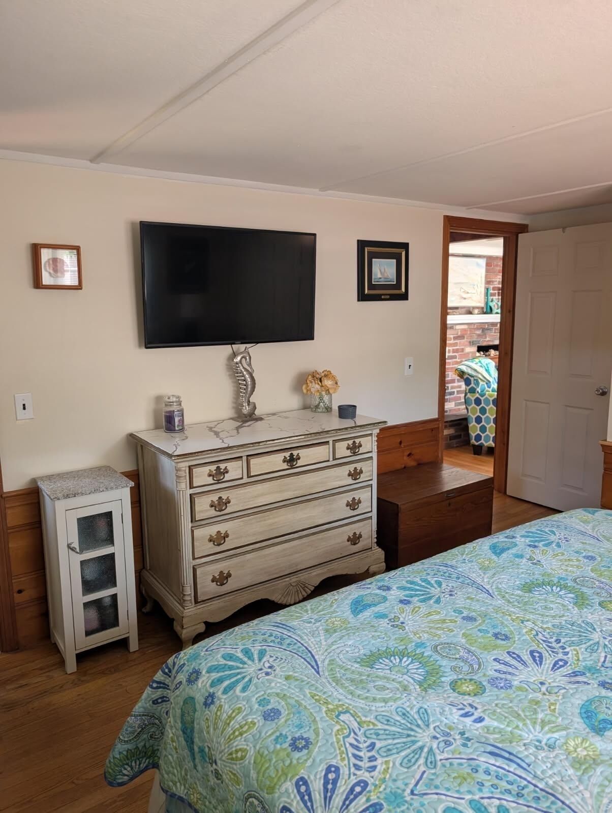 A bedroom with a bed, a dresser, a television, and a small cabinet.