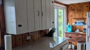 Una cocina con armarios blancos, un lavamanos de acero inoxidable y piso de madera.