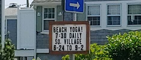 A street sign for South Village Beach with a yoga class schedule.