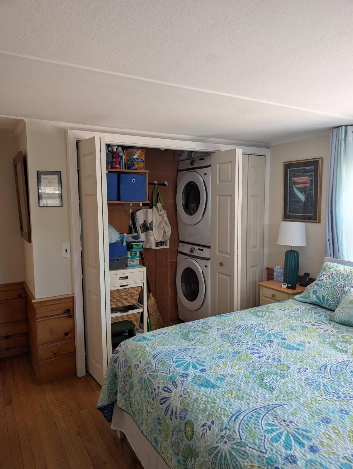 A compact bedroom with a bed, a washing machine, a small desk, and a wardrobe.