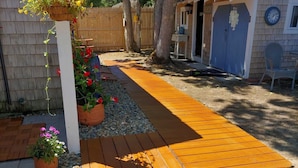 Una terraza de madera que lleva a una casa con una puerta azul que dice "BEACH".