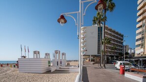 A beachside hotel with a white facade, palm trees, and a clear blue sky. - Loft Space - Time in Cádiz (Cádiz)