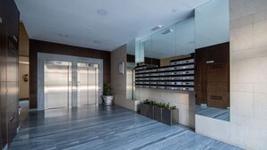 A modern lobby with a marble floor, two elevators, a potted plant, and a wall-mounted mailbox. - Loft Space - Time in Cádiz (Cádiz)