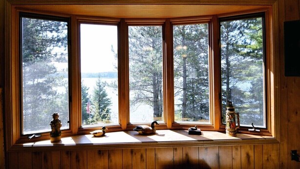A bay window with multiple panes, wooden paneled walls, and a view of trees and mountains. - Bony Lake North in Barnes, WI on Bony Lake with great access to AVT & Snowmobile Trails (Barnes)