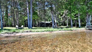A cabin with a clear view of the surrounding forest and a sandy beach. - Kitty Foye House on Upper Eau Claire Lake in Barnes (Barnes)