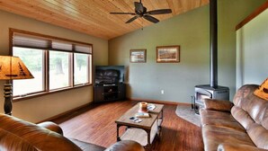 A cozy living room with a leather sofa, a wooden coffee table, a television, and a wood-burning stove. - Sugar Bay Sweets - Lake Namakagon (Cable)