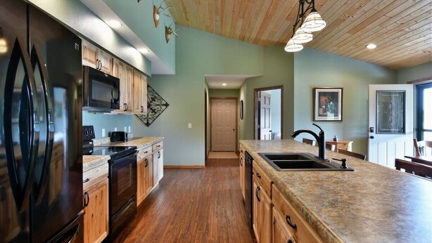 A kitchen with wooden cabinets, a stainless steel refrigerator, a microwave, and a granite countertop. - Sugar Bay Sweets - Lake Namakagon (Cable)