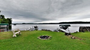 A lakeside campsite with a fire pit, a bench, and a covered area. - Sugar Bay Sweets - Lake Namakagon (Cable)