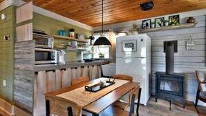 Una cocina con techo de madera, estufa empotrada y comedor con mesa y sillas.