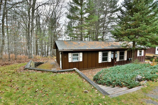 A cabin with a wooden exterior, a small porch, and a well-maintained lawn.