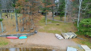 Un camping frente al lago con muelle, kayaks y una pequeña embarcación.