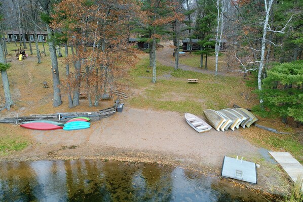A lakeside campsite with a dock, kayaks, and a small boat.