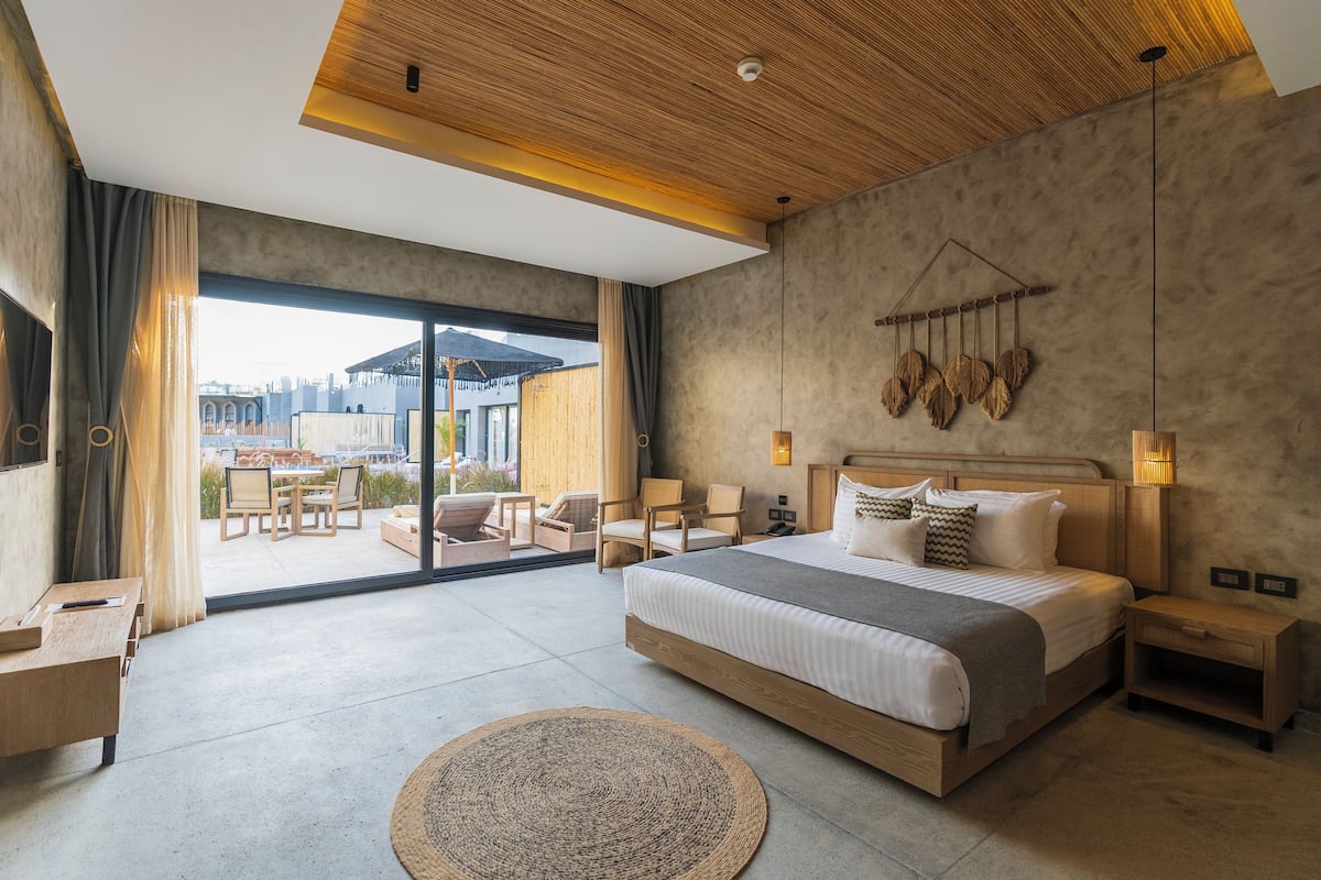 Une chambre moderne avec un grand lit, un plafond en bois et une vue sur l’extérieur.