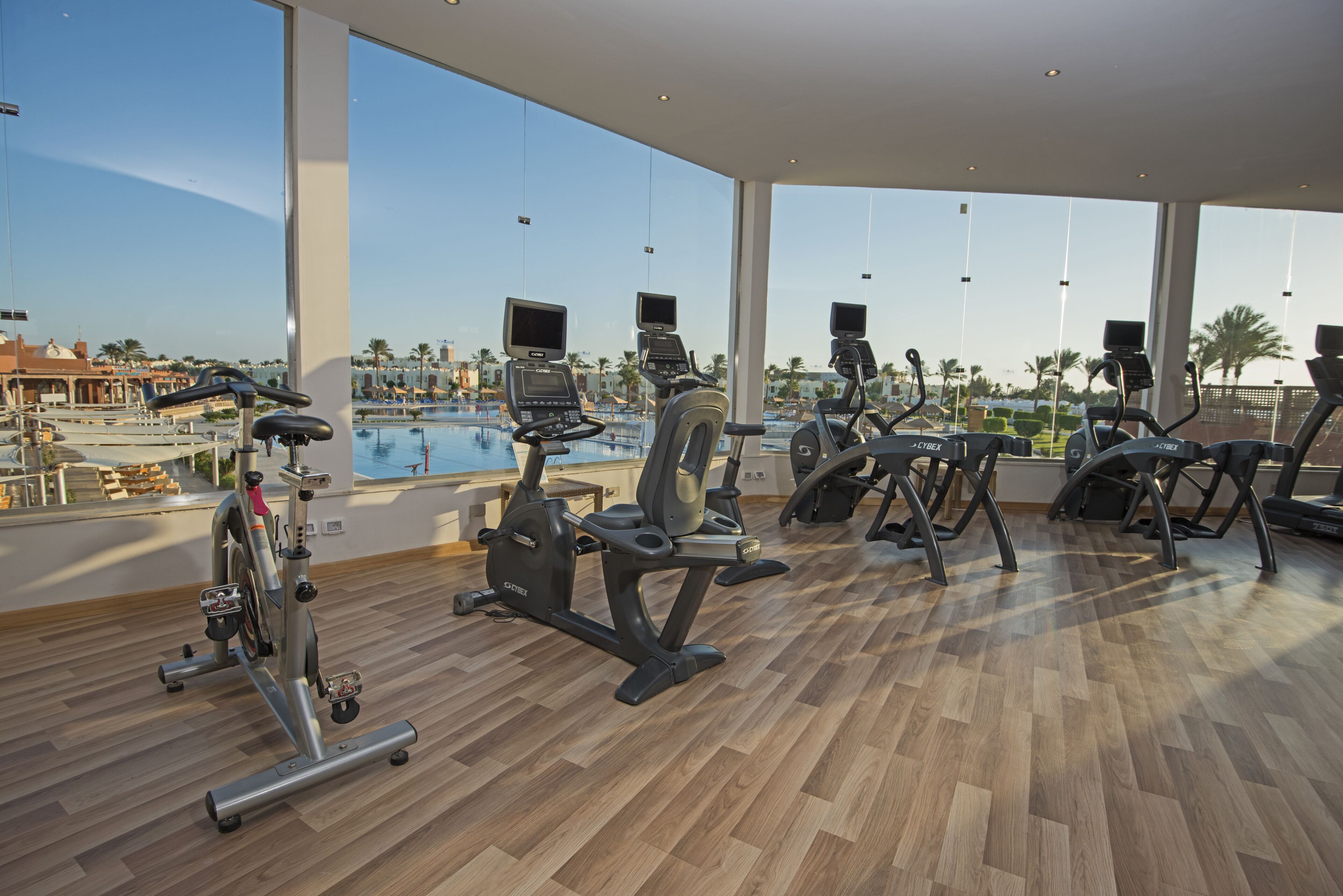 A gym with cardio machines and a pool view.