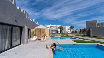 Relax by the rectangular pool surrounded by lounge chairs and umbrellas.