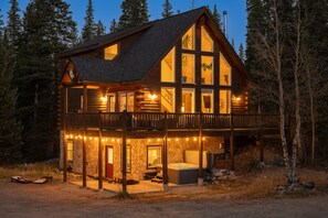 Eine Blockhütte mit Balkon, Whirlpool und einer Fassaden aus Stein.
