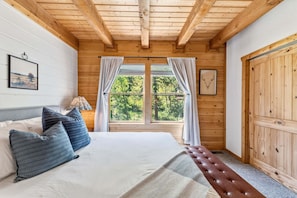 A wooden-paneled room with a bed, a bench, and a door.