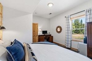 A bedroom with a bed, a desk with a computer, a window with curtains, and a radiator. - Custom Craftsman Chalet🏡Fenced Yard for Pets🍃Aspens, Hot Tub 💰$0 Cleaning & Pet Fee (Fairplay)
