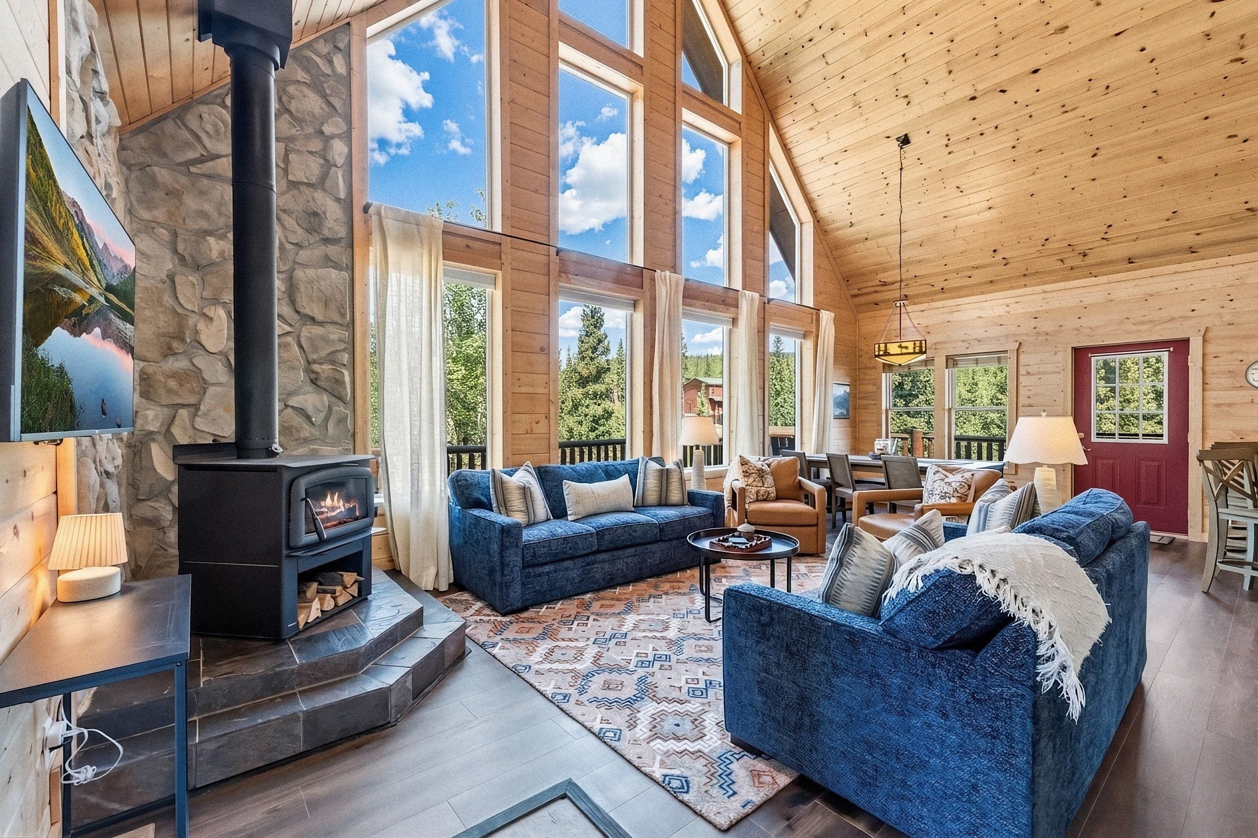 A spacious living room with a stone fireplace, large windows, and a cozy seating area.