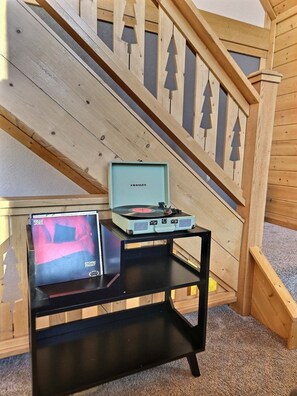 Un escalier avec des rampes en bois et une table noire sur laquelle se trouvent une platine et un disque vinyle.