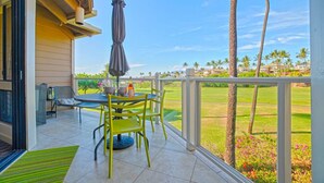 A covered outdoor area with a table and chairs, a bottle, and an umbrella.