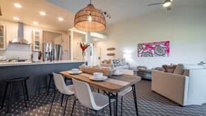 A modern kitchen with a dining area, a ceiling fan, and a wall art piece.