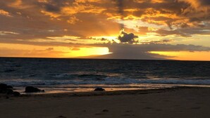 A beach with a sunset and ocean waves.